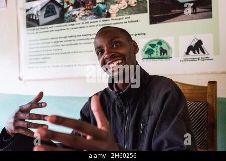 Septembre 2017.Le guide, Phillip Byarugaba, travaille pour la Nkuringo Community conservation and Development Foundation (NCCDF) qui accueille la visite du sentier forestier de la communauté de Buniga.Phillip traduit pour le guide Batwa qui partage sa culture dans sa langue locale.Les Pygmées Batwa ont été expulsées de leurs terres d'origine dans la forêt au début des années 1990, lorsque les parcs nationaux ont été établis, les laissant sans terre et pauvres dans une société qui les considérait comme une classe inférieure.Aujourd'hui, certains d'entre eux essaient de faire la rencontre des extrémités en organisant des promenades sur les sentiers; des visites culturelles qui incluent des exemples de l'endroit et de la façon dont ils utilisent pour vivre dans le Banque D'Images
