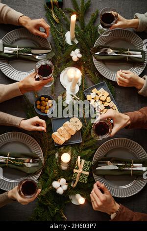 Vue de dessus arrière-plan de quatre personnes appréciant le dîner de Noël ensemble tout en étant assis à côté d'une table à manger élégante avec des bougies allumées, salle de copie Banque D'Images