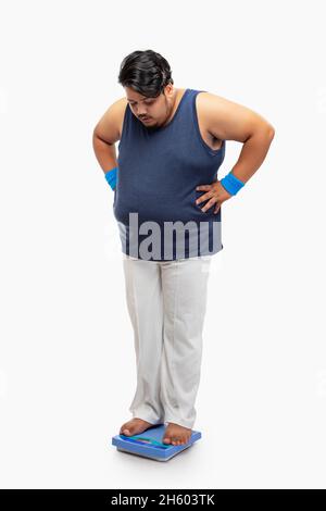 Portrait d'un gros homme debout sur la machine de pesage et mesurant le poids. Banque D'Images