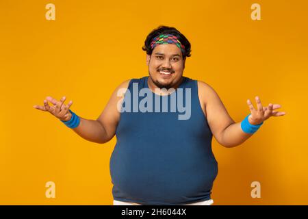 Portrait d'un gros homme souriant et haussant avec les mains sur fond plat. Banque D'Images