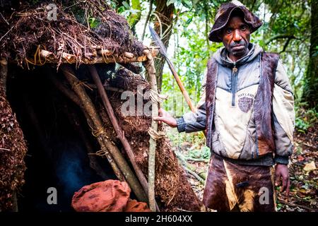 Septembre 2017.Le guide Batwa, Machate Emanuel, dirige la visite du sentier forestier communautaire de Buniga dans sa langue locale, les Pygmées de Batwa ont été expulsées de leurs terres d'origine dans la forêt au début des années 1990, lorsque les parcs nationaux ont été établis,les laisser sans terre et pauvres dans une société qui les considérait comme une classe inférieure.Aujourd'hui, certains d'entre eux essaient de faire la rencontre des extrémités en organisant des promenades sur les sentiers; des visites culturelles qui incluent des exemples de l'endroit et de la façon dont ils utilisent pour vivre dans la forêt, ainsi que du chant, de la danse et de l'artisanat pour la vente.Nkuringo, Ouganda. Banque D'Images