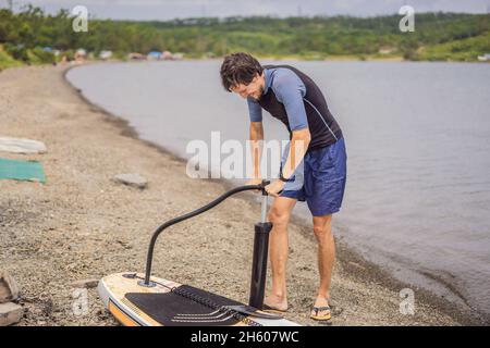 Le sportif gonfle le paddle Board, un divertissement moderne et à la mode Banque D'Images