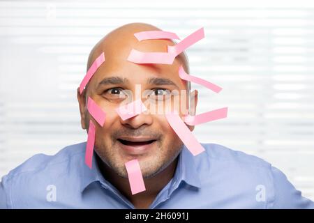 Portrait d'un homme chauve avec des notes collantes sur le visage, souriant. Banque D'Images
