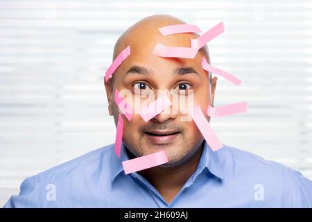 Portrait d'un homme chauve avec des notes collantes sur le visage, souriant. Banque D'Images