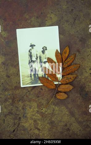 Imprimé photo sépia de deux femmes des années 1920 pagayant en mer peu profonde avec deux jeunes enfants et feuille brune sur laiton Banque D'Images