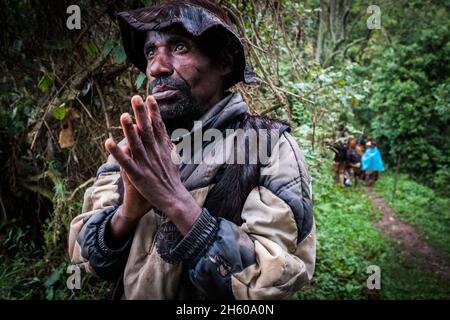 Septembre 2017.Le guide Batwa, Machate Emanuel, dirige la visite du sentier forestier communautaire de Buniga dans sa langue locale, les Pygmées de Batwa ont été expulsées de leurs terres d'origine dans la forêt au début des années 1990, lorsque les parcs nationaux ont été établis,les laisser sans terre et pauvres dans une société qui les considérait comme une classe inférieure.Aujourd'hui, certains d'entre eux essaient de faire la rencontre des extrémités en organisant des promenades sur les sentiers; des visites culturelles qui incluent des exemples de l'endroit et de la façon dont ils utilisent pour vivre dans la forêt, ainsi que du chant, de la danse et de l'artisanat pour la vente.Nkuringo, Ouganda. Banque D'Images