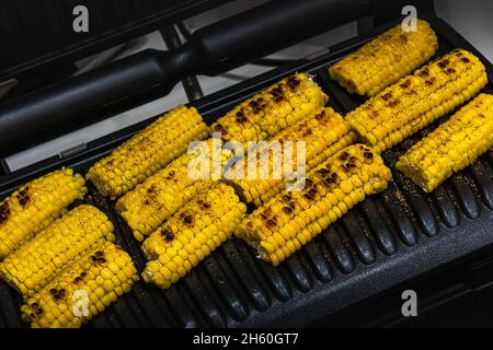 Tranches de épis de maïs doux jaunes savoureux et grillés sur la surface du gril en métal noir.Certaines graines brunes ont une surface légèrement brûlée.cuisin mexicain Banque D'Images