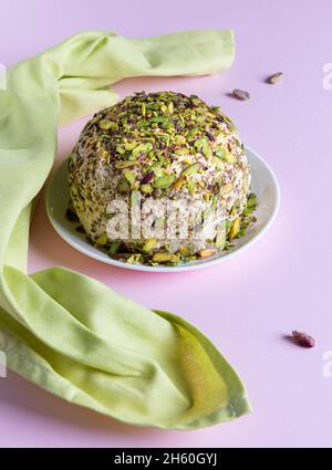 Halva de sésame avec pistaches, quelques noix rouges et serviette en lin vert sur papier rose.Vue grand angle.Bonbons traditionnels du Moyen-Orient.Juif, tu Banque D'Images