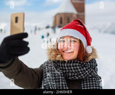 jeune femme souriant et prenant un selfie en paysage d'hiver avec un arrière-plan flou Banque D'Images