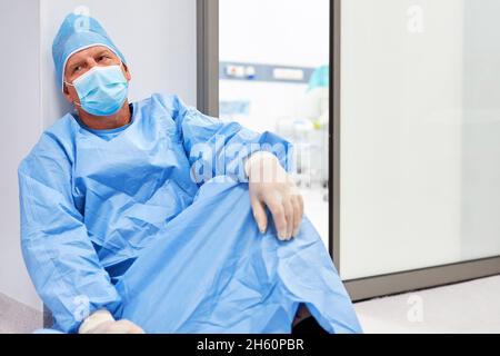 Médecin en vêtements de protection est brûlé et fatigué sur le sol devant l'unité de soins intensifs de la clinique Banque D'Images