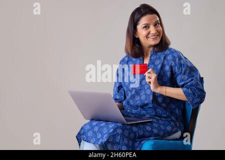 Femme indienne affichant sa carte de crédit pendant les achats en ligne Banque D'Images