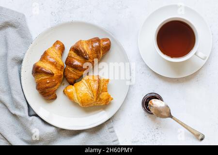 Ambiance petit déjeuner.Croissants sur plaque et tasse de thé. Banque D'Images