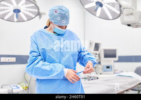 Médecin comme chirurgien avec masque de visage met sur la robe avant l'opération dans la chirurgie Banque D'Images