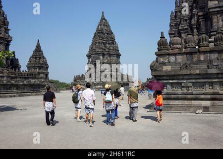 Groupe de peuples asiatiques avec guide de visite à pied autour de l'ancien complexe du temple hindou de Prambanan.Fond ciel bleu clair et ensoleillé. Banque D'Images