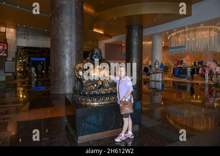 Nevada USA 09-06-21 à la recherche de chance, une dame pose pour une photo touchant le ventre du Bouddha heureux (Ho Tai) situé à l'ARIA Las Vegas casino Banque D'Images