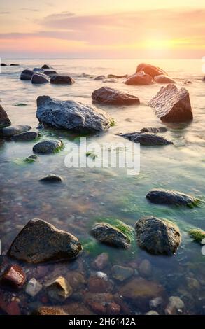 Rocky plage de la mer Baltique au coucher du soleil. Banque D'Images