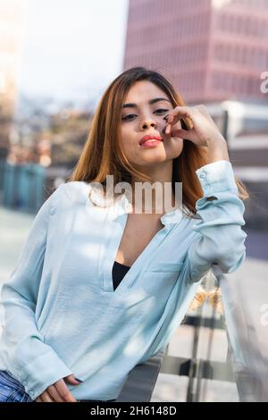Gros plan de la belle femme d'affaires latine avec de longs cheveux droits regardant l'appareil photo dans la ville.Concept d'affaires et de beauté Banque D'Images