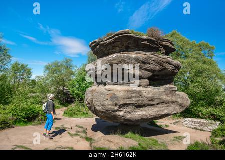 Idol Rock, vue en été d'une femme d'âge moyen regardant Idol Rock, une énorme formation rocheuse érodée équilibrée sur son propre axe, Brimham Rocks, Yorkshire Banque D'Images