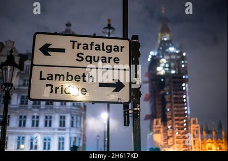 LONDRES - 1 NOVEMBRE 2021 : panneau de signalisation routière directionnel avec les chambres du Parlement hors de point dans l'arrière-plan la nuit Banque D'Images