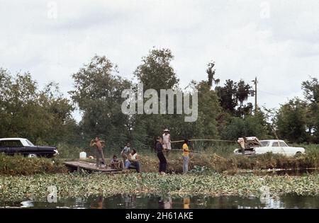 Famille afro-américaine et amis appréciant un moment amusant de pêche et de jouer sur les rives d'un Bayou en Louisiane ca.Août 1972 Banque D'Images