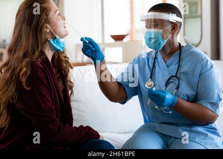 Femme médecin dans un masque facial protecteur prenant un test d'écouvillonnage de la femme en clinique pendant la crise du coronavirus Banque D'Images