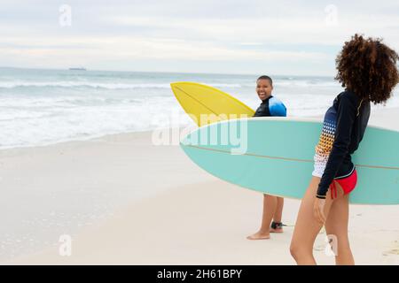 Des amies multiraciales avec planches de surf sur la plage pendant le week-end Banque D'Images