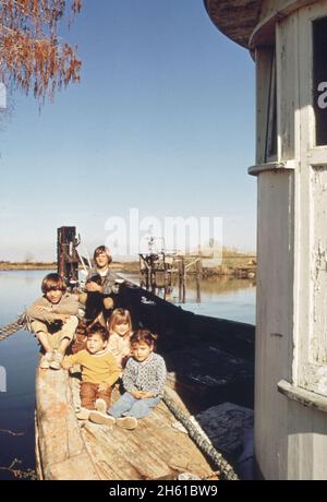 Enfants de pêcheurs sur un vieux bateau de pêche.Puits de gaz en arrière-plan; Bayou gauche Louisiane ca.Février 1973 Banque D'Images