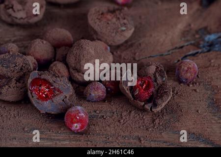 Truffes de canneberges biologiques faites maison en chocolat noir et baies congelées sur une table en chêne massif.Truffes végétaliennes pour un dessert sain. Banque D'Images