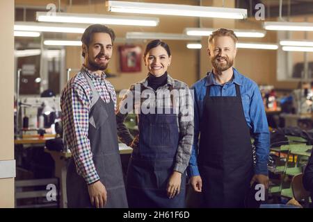 Portrait de trois Caucasiens expérimentés souriants ouvriers d'usine de chaussures et de vêtements au travail. Banque D'Images
