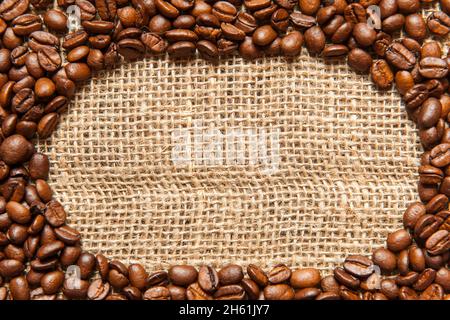 Cadre ovale en grains de café torréfiés sur une toile à sacoches pour un format plus plein. Banque D'Images