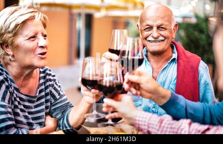 Un couple senior heureux qui s'est amusé à boire du vin rouge avec des amis lors d'une soirée dîner - des personnes refatiguées mangent sur le balcon du restaurant ensemble Banque D'Images