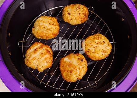 boulettes de poulet cuites dans de la chapelure sur la grille en acier de l'airfryer ouvert - gros plan Banque D'Images