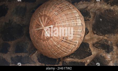 Le panier en bambou tricoté à la main est accroché au mur Banque D'Images