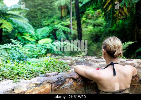 Vue arrière d'une femme se baignant dans les piscines thermales de Caldeira Velha, Sao Miguel, Açores, Portugal Banque D'Images