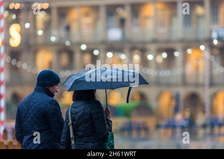 Un couple porte un parapluie comme ils font leurs achats de Noël dans le Halifax Piece Hall , Calvaire , West Yorkshire.Le mauvais temps et la forte pluie ne les ont pas stoppe. Banque D'Images