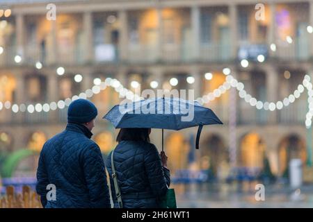 Un couple brave la pluie dans le Halifax Piece Hall, à Calvaire, dans le West Yorkshire, pour faire ses courses de Noël dans le bâtiment historique . Banque D'Images