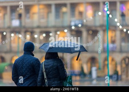 Un couple brave la pluie dans le Halifax Piece Hall, à Calvaire, dans le West Yorkshire, pour faire ses courses de Noël dans le bâtiment historique . Banque D'Images