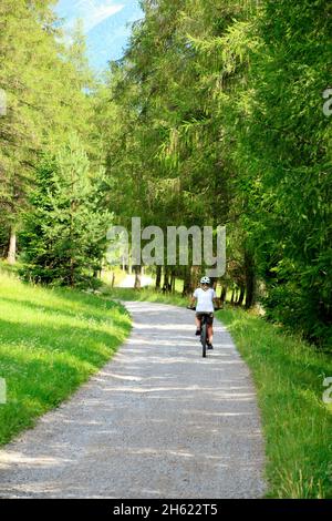 cycliste,cycliste femelle de derrière avec casque,autriche,tyrol,plateau mieminger,obermieming,vue sur la ville à l'extérieur,été,prairies,prairie,prairies d'été,e-bike Banque D'Images