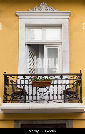 Balcon sur un bâtiment jaune pastel dans le centre-ville de Vegueta, Las Palmas.Petite terrasse sur façade avec pot en argile, deux chaises et une table Banque D'Images