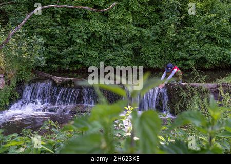 europe,allemagne,bade-wurtemberg,région de schönbuch,waldenbuch,boy bénéficie d'une belle journée de printemps par un ruisseau dans la forêt Banque D'Images