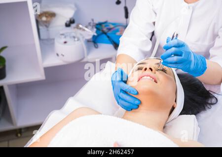 Femme dans le salon de beauté subit une microdermabrasion faciale procédures de rajeunissement, cosmetologiste professionnel faisant son travail. Banque D'Images