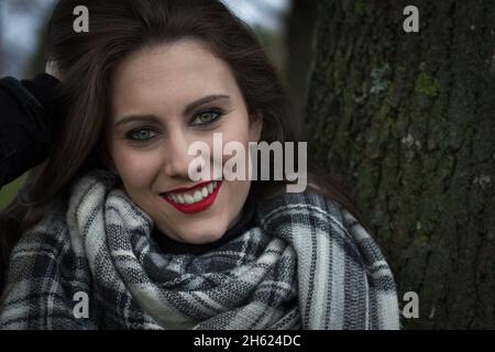 Beau gros plan de sourire belle fille avec des yeux verts étonnants.Portrait d'une jeune femme brune avec des cheveux longs et du maquillage, à l'extérieur Banque D'Images