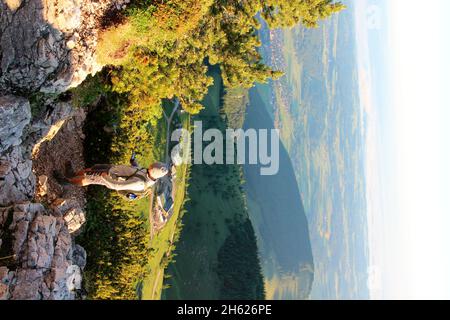 jeune homme en randonnée au sommet de kampenwand (1669 m) à chiemgau, téléphone cellulaire, tour, gps, lever du soleil, alpes de chiemgau, chiemsee, près d'aschau, haute-bavière, bavière, sud de l'allemagne, allemagne Banque D'Images