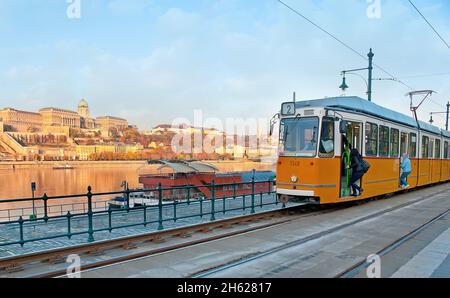 Le tramway jaune vintage s'est arrêté à la gare de Belgrade Quay avec une vie gagnée Danube et le château de Buda sur la rive opposée, Budapest, Hungar Banque D'Images