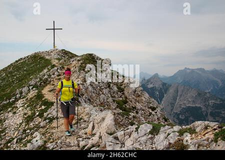 jeune femme sur la randonnée depuis le sommet de la brunnsteinspitze (2197 mètres), dans la vallée, de l'avant, sommet croix en arrière-plan, autriche, tyrol, scharnitz, karwendel parc naturel, Banque D'Images