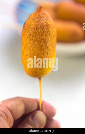 L'homme tient le chien de maïs cuit avec des saucisses et de la pâte de blé avec l'addition de farine de maïs Banque D'Images