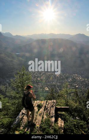 une jeune femme regardant vers l'avant dans le contre-jour, en arrière-plan les alpes de kranzberg, ammergau photographiés sous le soleil à la cabane mittenwalder sur le karwendel, mittenwald, haute-bavière, vallée d'isar, bavière, allemagne, europe Banque D'Images