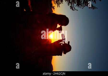 deux jeunes femmes,snack,boisson,bouteille de shilouette,réjouissez-vous dans le contre-jour,coucher de soleil,photographié à la cabane mittenwalder sur le karwendel,mittenwald,haute-bavière,vallée d'isar,bavière,allemagne,europe, Banque D'Images