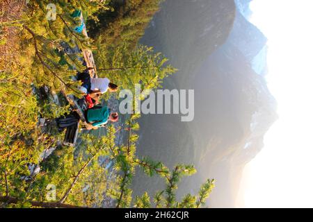 deux jeunes femmes,snack,sont heureux dans le contre-jour,coucher de soleil,photographié à la cabane mittenwalder à la karwendel,mittenwald,haute-bavière,vallée d'isar,bavière,allemagne,europe,larches,branches de mélèze Banque D'Images