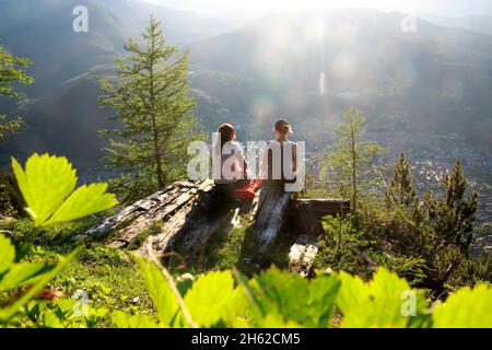 deux jeunes femmes, snack, sont heureux dans le contre-jour, dans le fond le kranzberg, wettersteingebirge estergebirge au coucher du soleil, photographié à la cabane de mittenwalder am karwendel, mittenwald, haute-bavière, vallée d'isar, bavière, allemagne, europe Banque D'Images